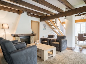 A cozy living room with a fireplace, comfortable seating, and a staircase leading to another level. - Peaceful Farmhouse in De Cocksdorp near Sea (De Cocksdorp)