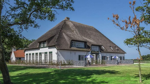 Il s’agit d’un bâtiment traditionnel, doté d’un toit de chaume, de grandes fenêtres et d’un mur de pierre à l’avant.
