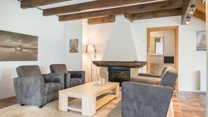 Un salon avec une cheminée, des canapés, une table basse et des œuvres d’art accrochées aux murs.