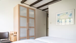 Une chambre à coucher avec un lit, une armoire en bois aux portes vitrées, une chaise et une carte accrochée au mur.