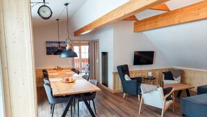 A spacious living area with a wooden dining table, chairs, and a television mounted on the wall. - Modern Apartment Right Next to the ski Lift (Sankt Margarethen im Lungau)