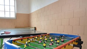 A foosball table and a ping pong table in a room with brick walls and a window. - Ferienwohnung mit Garten auf dem Bauernhof (Trendelburg)