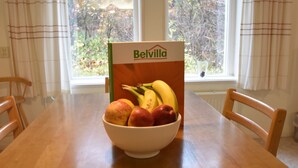 A wooden dining table with a bowl of fruit and a Belvilla box. - Apartment Bergen aan Zee Near Beach (Bergen aan Zee)