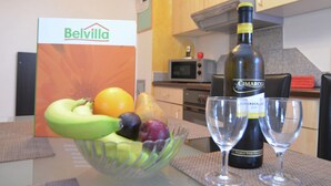 A kitchen with a table set for two, featuring a bottle of Cimarosa wine, two wine glasses, and a bowl of fruit. - Gemutliche Ferienwohnung, Lechbruck (Lechbruck)