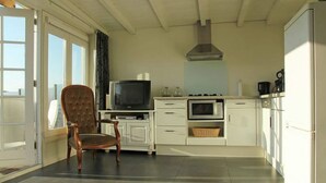 Une cuisine compacte équipée d’une télévision, d’un four et de meubles blancs.