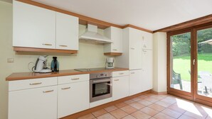 A kitchen with white cabinets, a built-in oven, and a coffee maker. - Rustic Cottage in Jevigne (Lierneux)