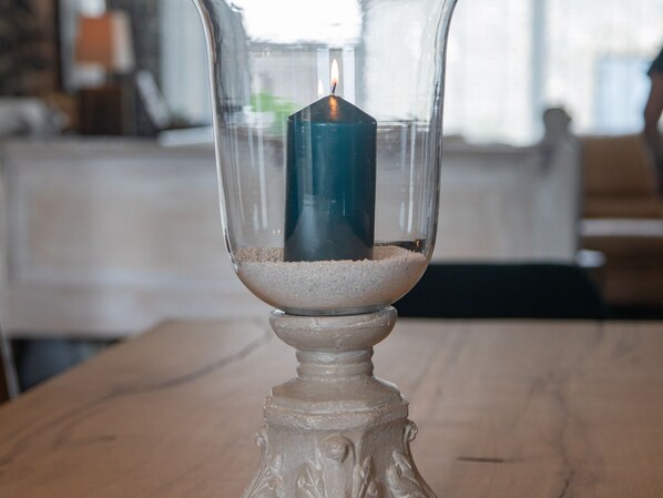 A candle in a glass holder on a wooden table.