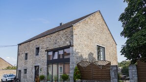 A stone building with a modern window design, a gated entrance, and potted plants in front. - Tranquil Stay in Ardennes (Doische)