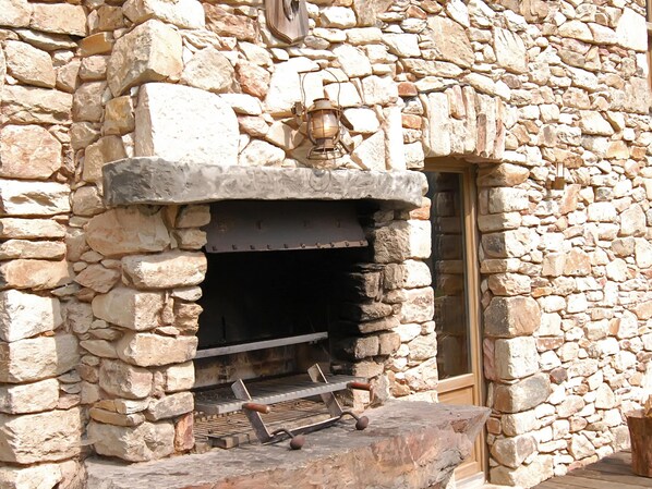 A stone building with a fireplace, a wooden bench, and a lantern. - Opulent Chalet in Thirimont With Turkish Steambath (Waimes)