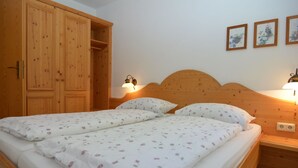 A bedroom with a wooden bed, two nightstands, a wall-mounted lamp, and a wardrobe.