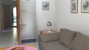 A living room with a sofa, a small table with a lamp, and a wooden bowl on a pink mat.