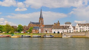 Un río con barcos amarrados a la izquierda, un puente a la derecha y edificios históricos al fondo.