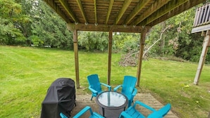 A covered patio area with a round table and four blue chairs, surrounded by a wooden pergola. - Charming 2-unit retreat in Rockford (Rockford)