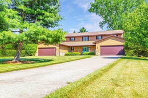 A two-story house with a driveway, a garage, and a well-maintained lawn.