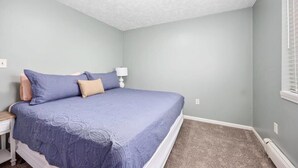 A bedroom with a bed, nightstand, and a window with blinds. - Charming 2-unit retreat in Rockford (Rockford)