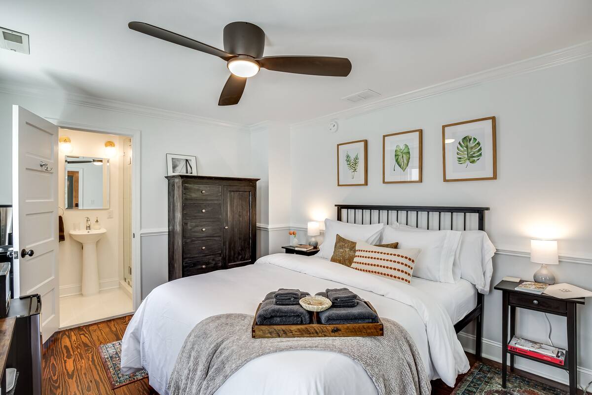 A neatly arranged bedroom with a bed, bedside table, and a ceiling fan.