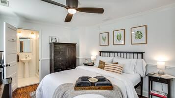 Un dormitorio ordenado con cama, mesita de noche y ventilador de techo.