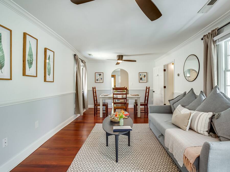 A living room with a gray sofa, a coffee table, and a dining area with a table and chairs.