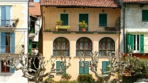 Um edifício com varanda, janelas em arco e telhado em telhas.