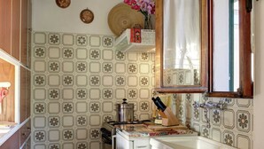 Uma cozinha com azulejos estampados, fogão, pia e janela com cortina.