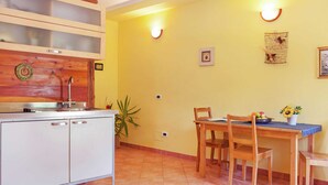 A kitchen with a wooden cabinet, a sink, and a dining table with chairs. - Cozy Cottage in Portomaggiore near Lake (Portomaggiore)