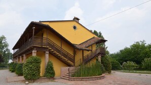 A yellow building with a wooden balcony and a staircase leading to a second-floor balcony. - Cozy Cottage in Portomaggiore near Lake (Portomaggiore)