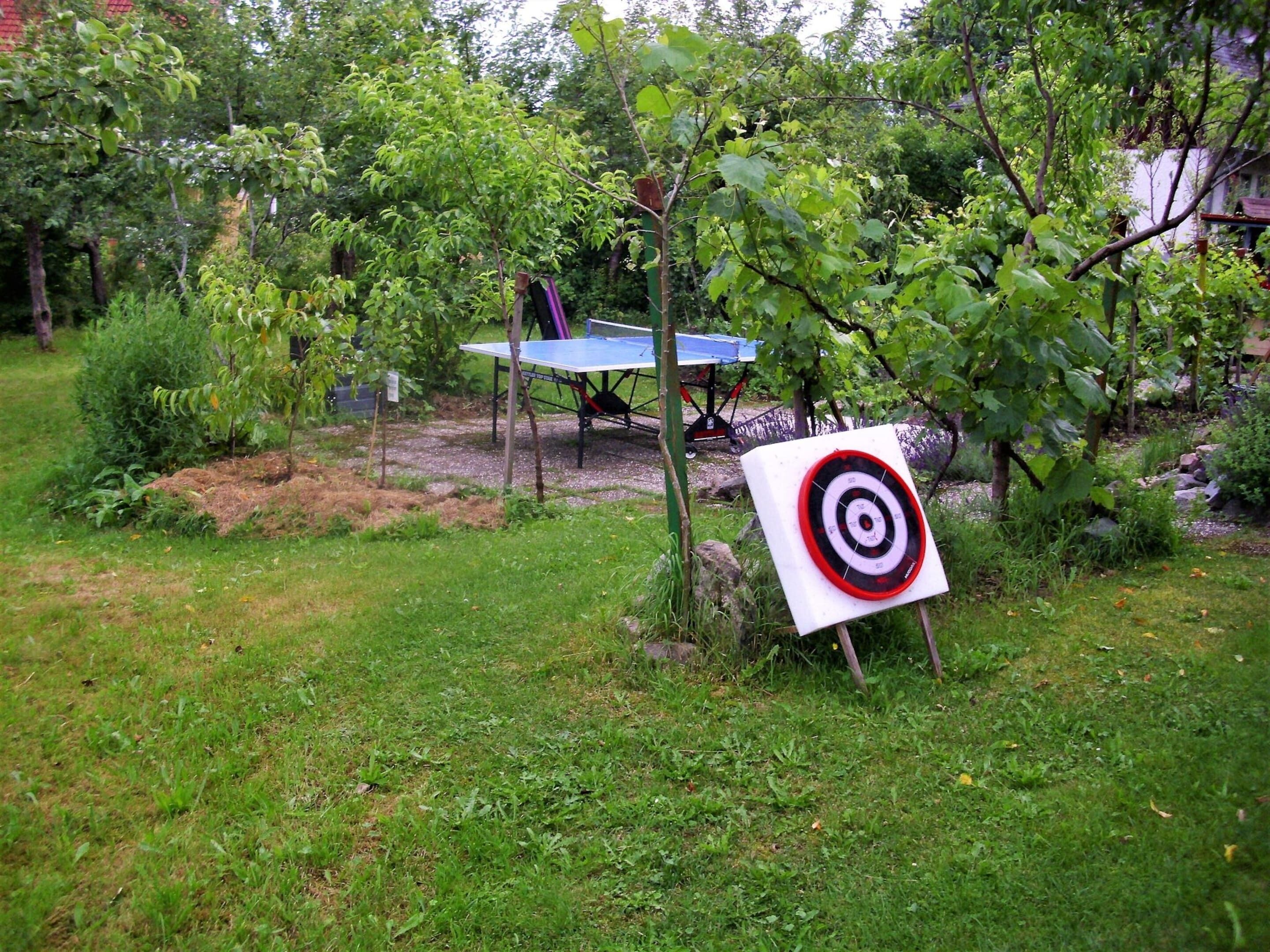 Een tuin met een dartbord, een tafel en een zonnepaneel.