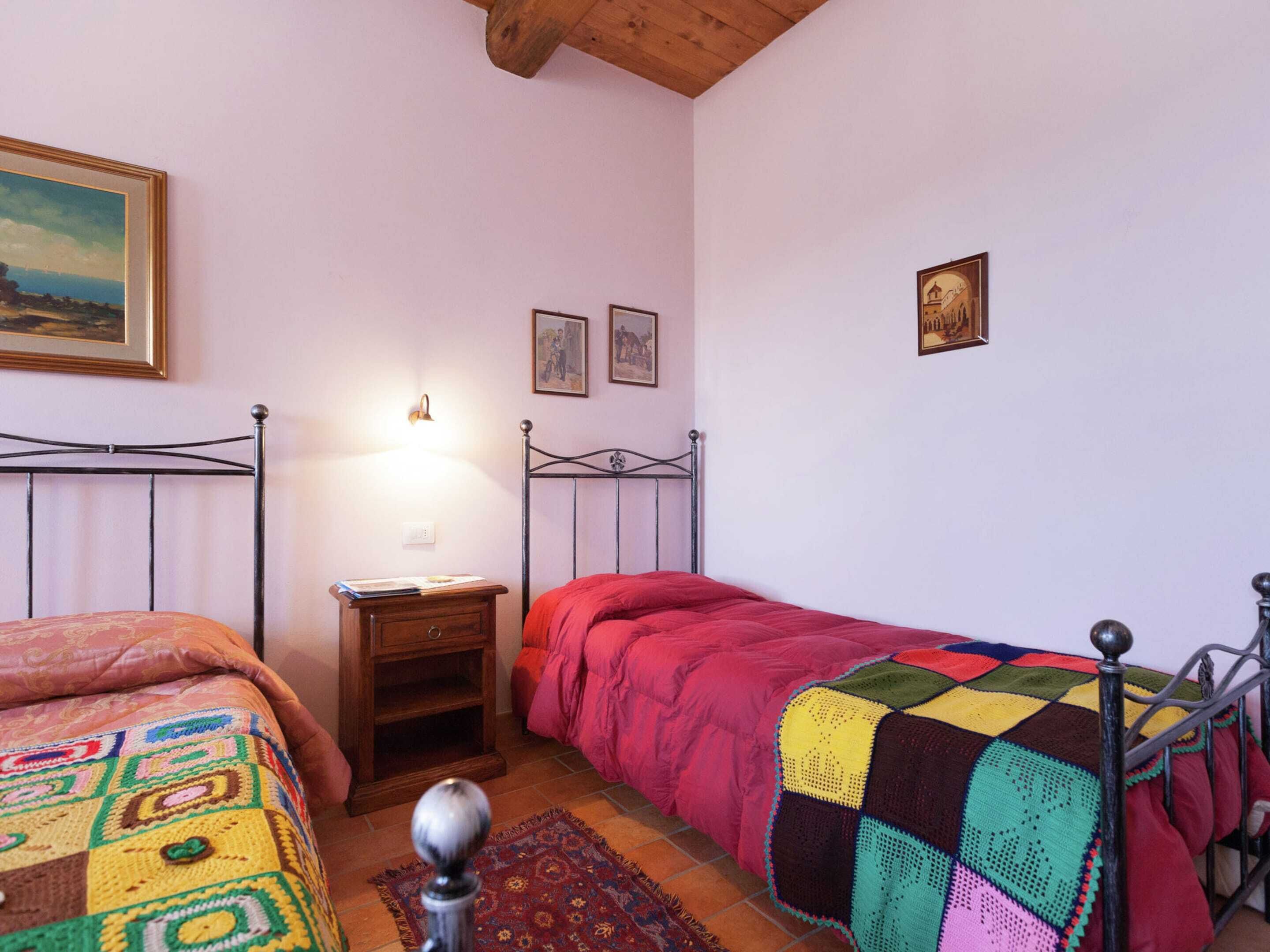 A bedroom with two beds, a nightstand, a lamp, and a small rug.