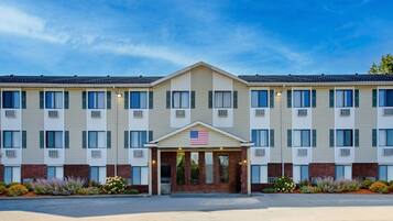 A multi-story hotel with a central entrance, American flag, and a brick facade.