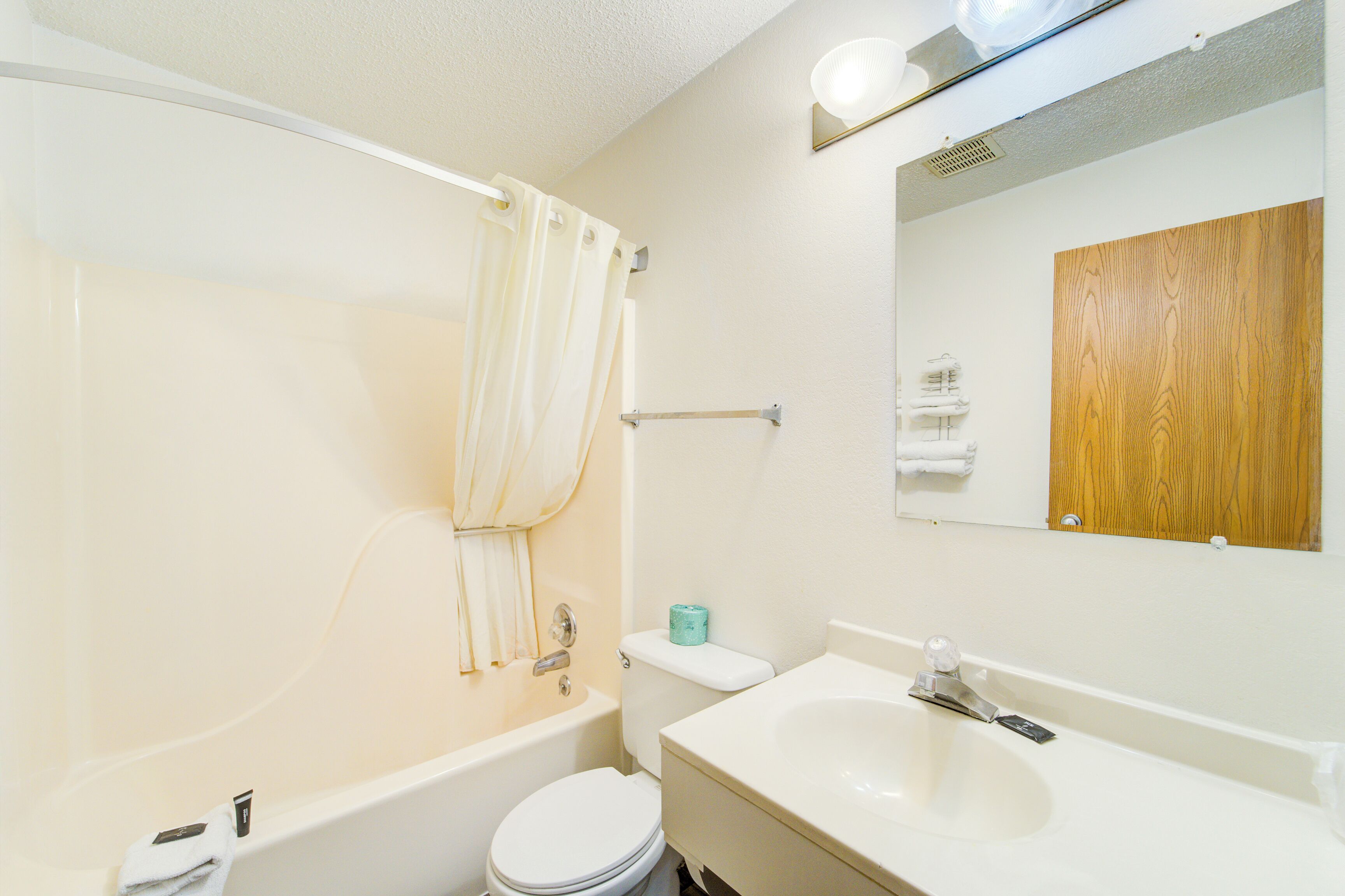 Et badeværelse med badekar, toilet, vask og en træpanel på væggen.
