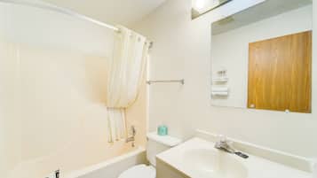 A bathroom with a bathtub, toilet, sink, and a wooden panel on the wall.