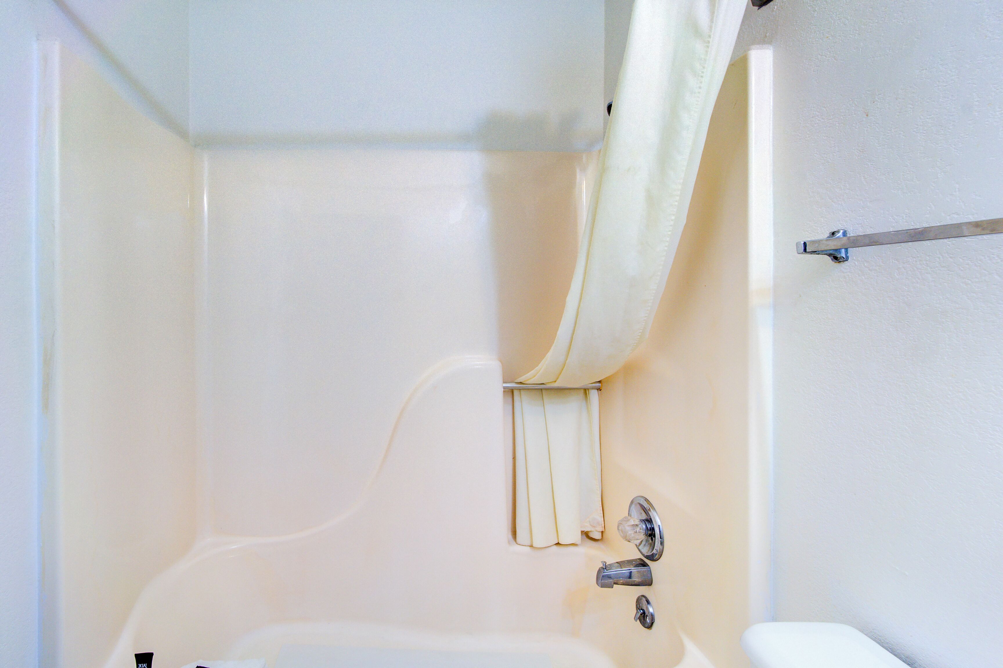 A bathroom with a bathtub, a shower curtain, and a towel rack.