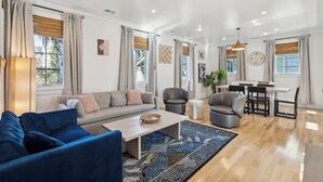 A spacious living room with a sofa, armchairs, a coffee table, and a dining area with chairs and a table. - Luxurious Private Suites in Downtown Charleston (Charleston)