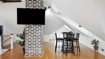 Ein modernes Loft mit einer Ziegelwand, einem Flachbildfernseher, einem Essbereich mit Holzboden und einer Treppe.