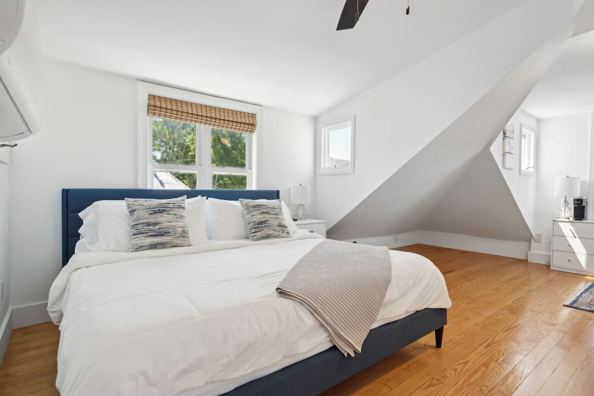A bedroom with a bed, a nightstand, a dresser, and a window with blinds.
