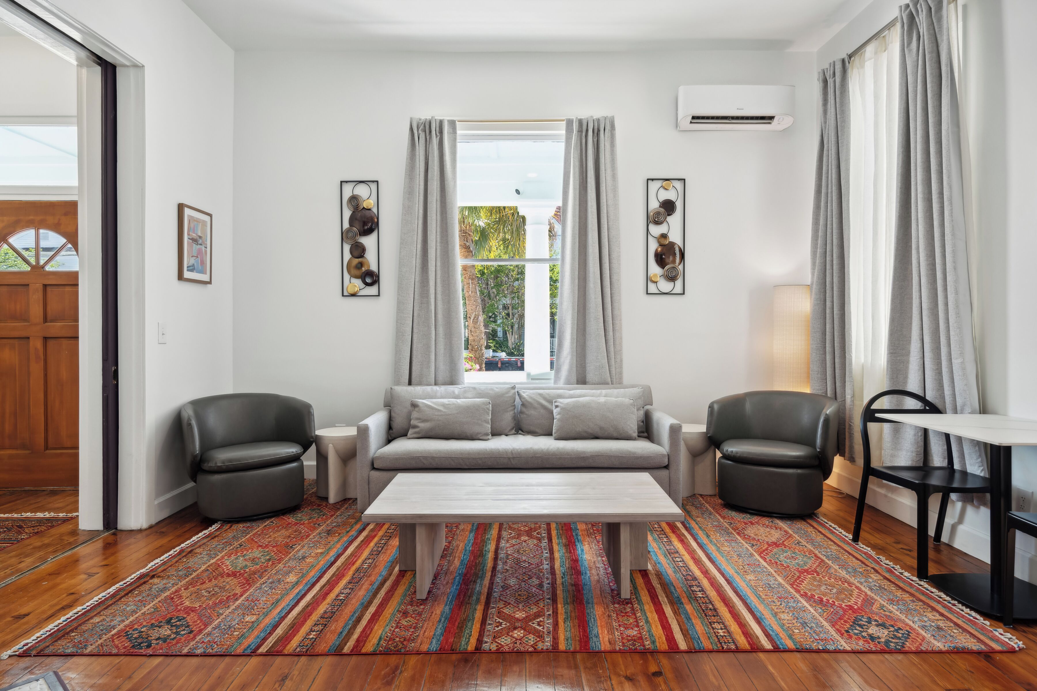 A living room with a sofa, two armchairs, a coffee table, and a patterned rug.