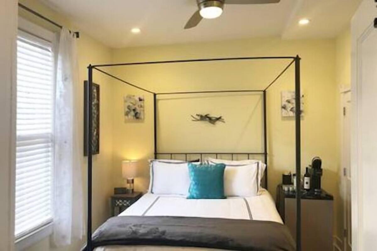 A four-poster bed with a headboard, a bedside table, and a lamp.