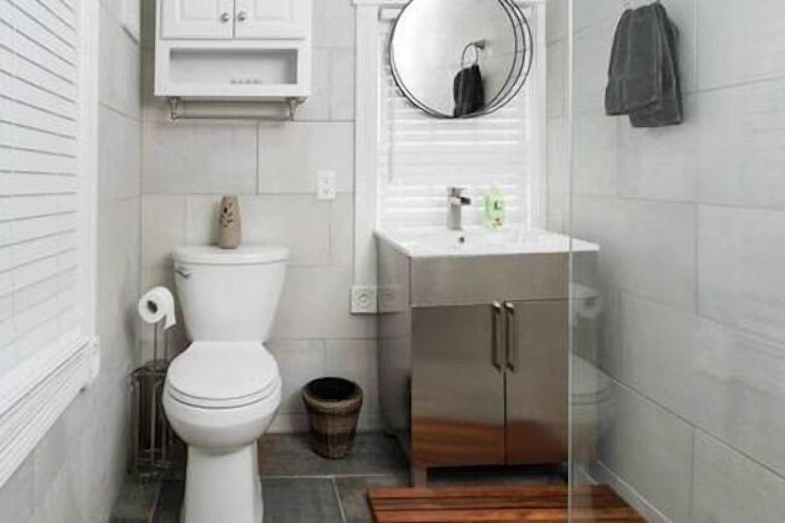 A modern bathroom with a toilet, sink, and mirror.