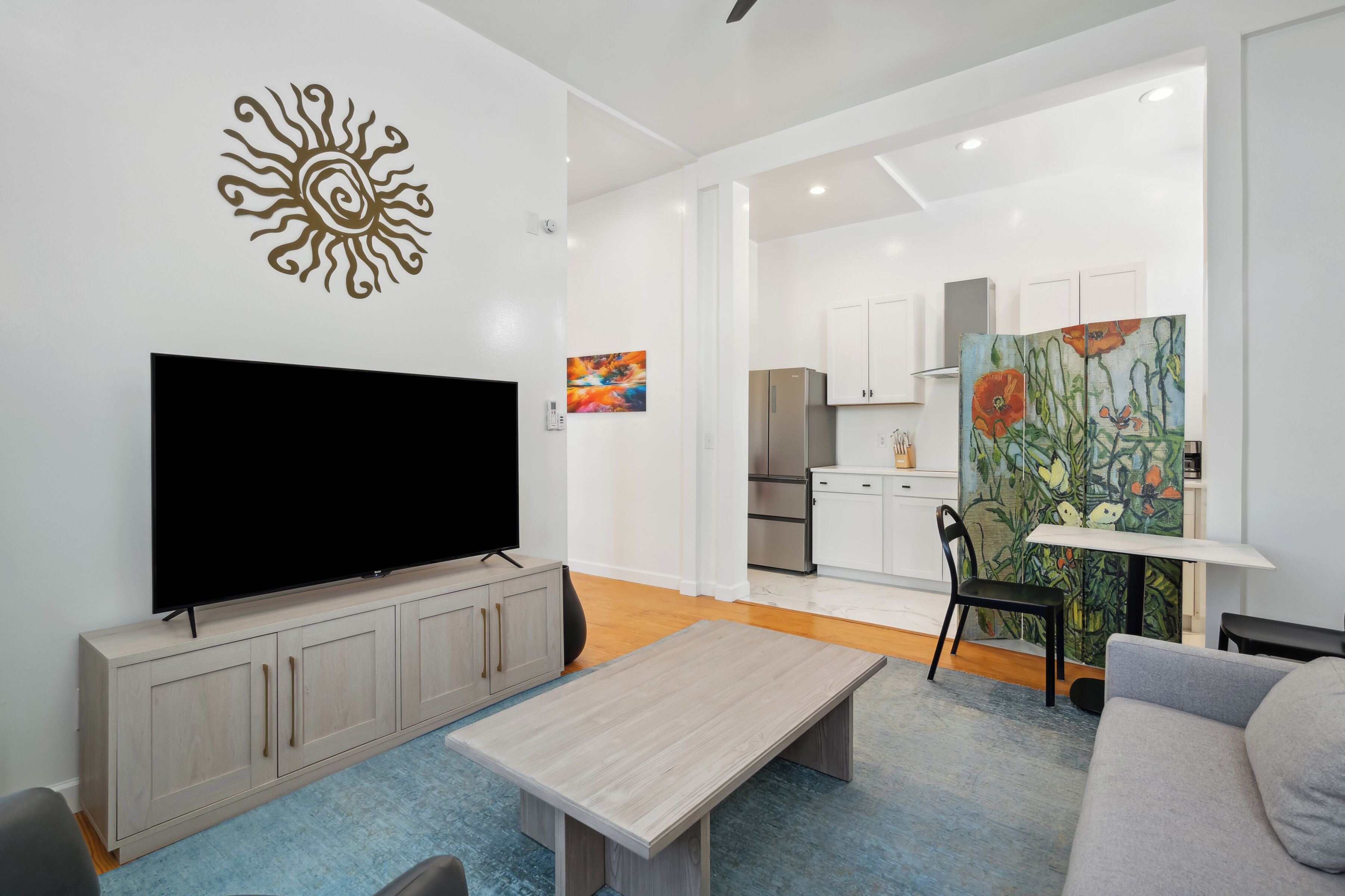 Una sala de estar moderna con una televisión de pantalla plana, una mesa de centro de madera y un sofá gris.