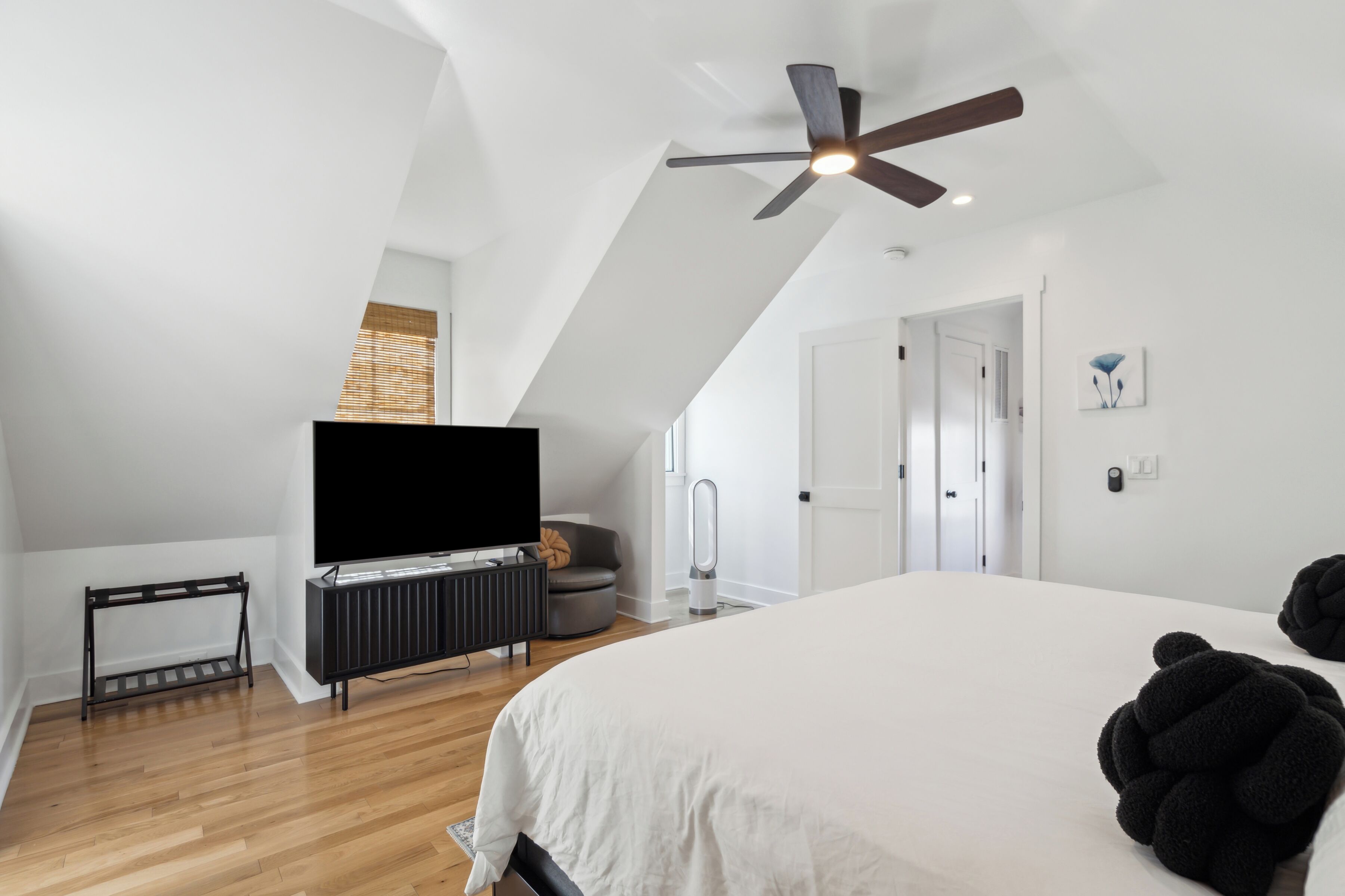 Une chambre avec un grand lit, un ventilateur de plafond, une télévision et un radiateur.