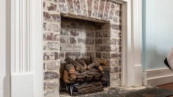 A fireplace with a stack of logs and a metal grate.