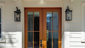 A double wooden door with glass panels, a checkered stone entrance, and two wall-mounted lanterns. - Luxurious Private Suites in Downtown Charleston (Charleston)