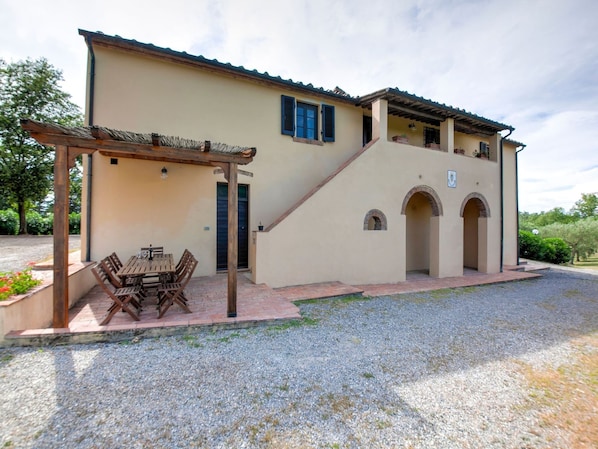 A two-story building with a covered patio area and a gravel driveway.