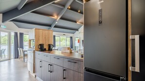 A modern kitchen with a built-in refrigerator, wooden cabinets, and a countertop with a coffee maker. - Well Furnished Home for Groups with Dishwasher near Water (Gasselternijveen)