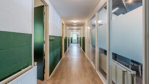 A long, narrow hallway with a wooden floor and green walls, leading to a door labeled "LADY." - Well Furnished Home for Groups with Dishwasher near Water (Gasselternijveen)