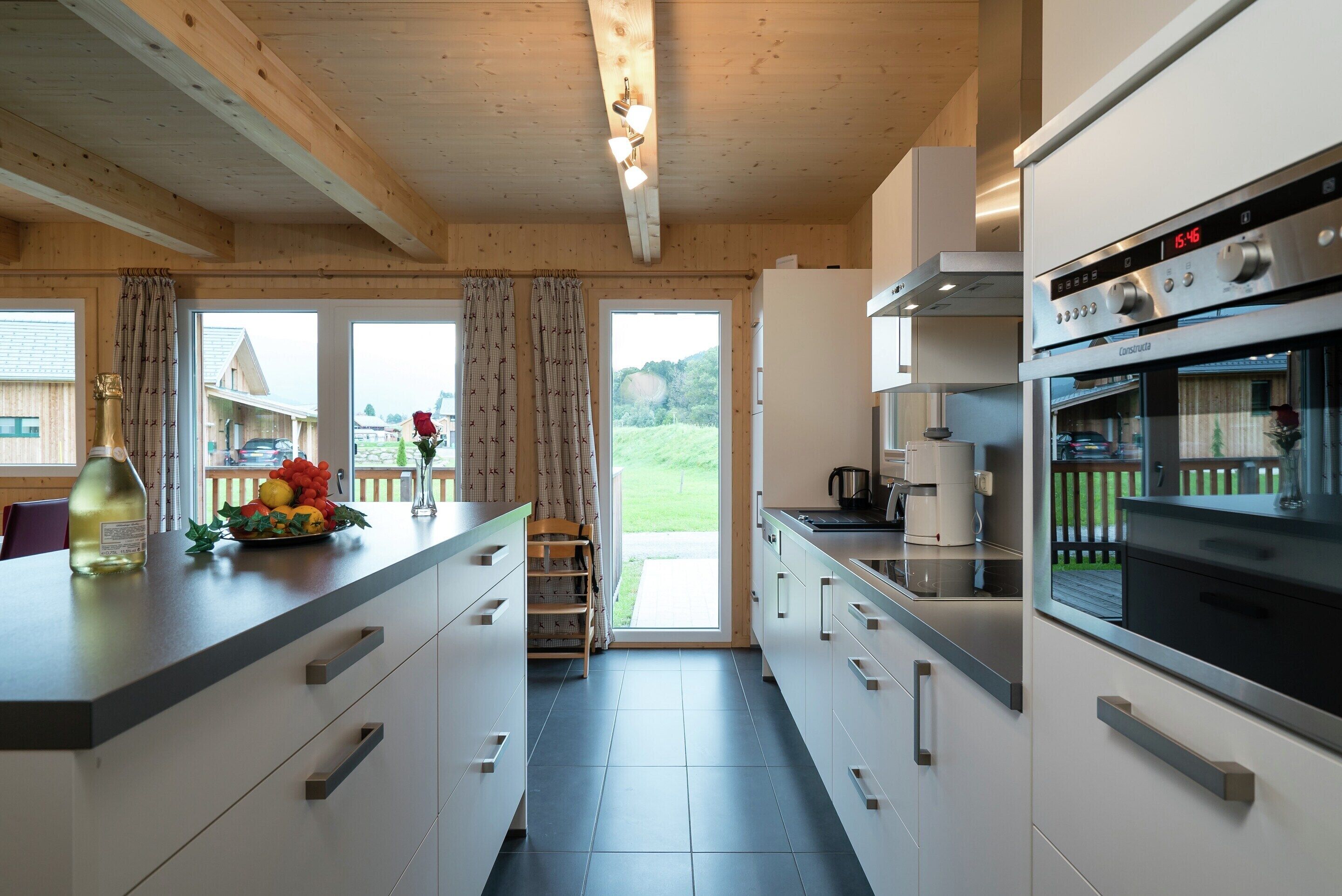 A modern kitchen with a central island, stainless steel appliances, and a view of the outdoors.