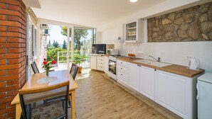 Une cuisine moderne avec des armoires blanches, un plan de travail en bois et un pare-feu en pierre.