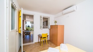 Une chambre d’hôtel avec un lit, une armoire en bois, une petite table avec une chaise et un miroir au mur.