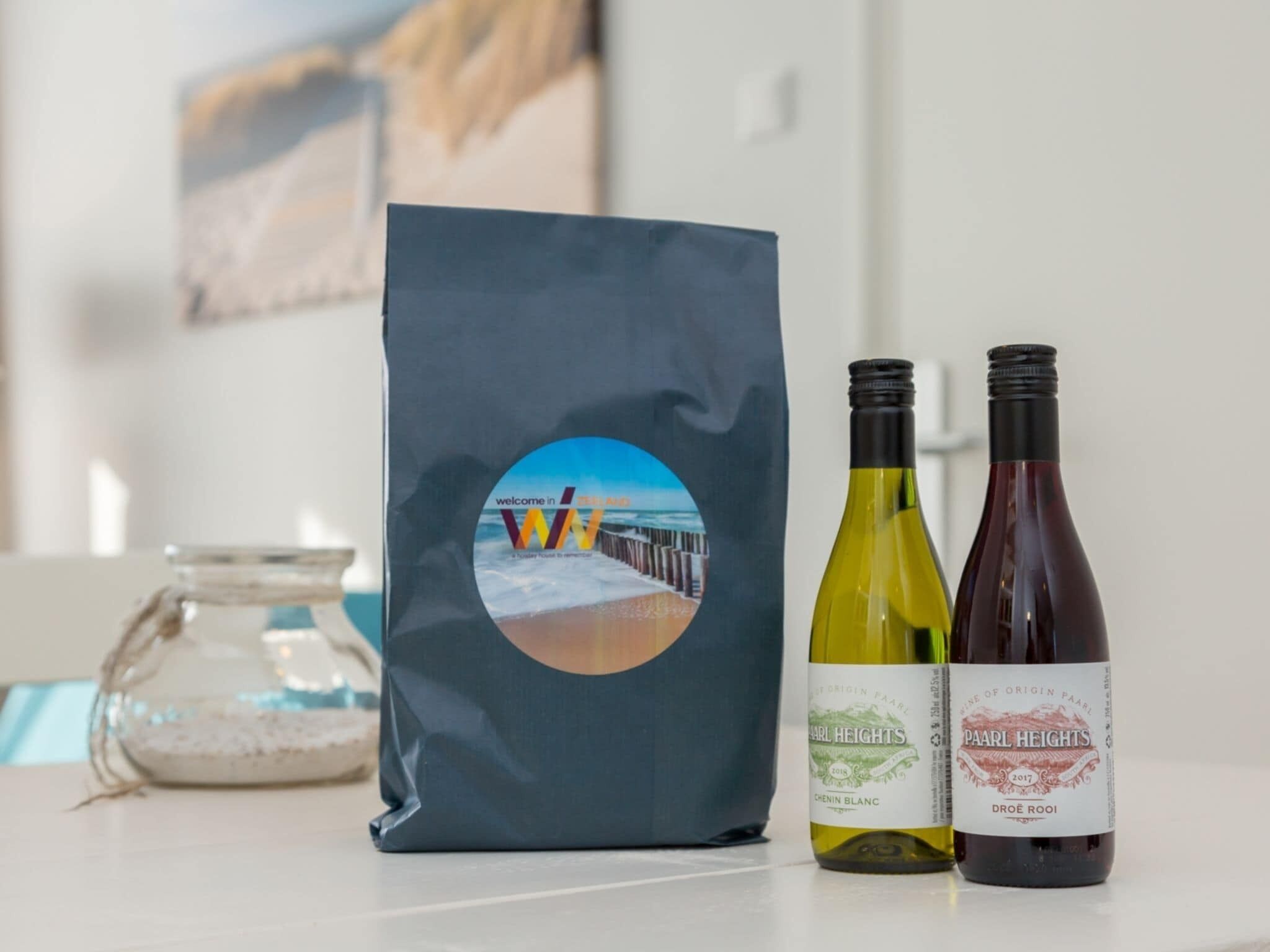 A bag with a scenic sticker, two wine bottles labeled 'PAARL HEIGHTS', and a glass jar.