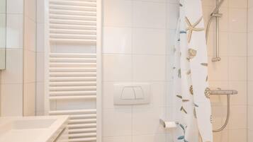 Een badkamer met een witte betegelde muur, een witte handdoekhouder, een douche met een gordijn met sterren en een toilet.